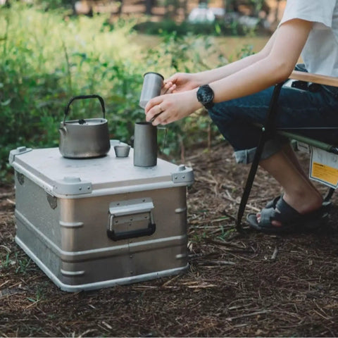 Rugged Folding Storage Box With Lid Heavy Duty Aluminum Frame Stackable Gear Crate Built Tough For Camping And Picnics No Sweat Organization Haul Your Stash On The Go Rust Resistant Silver Design with kettle and cups.