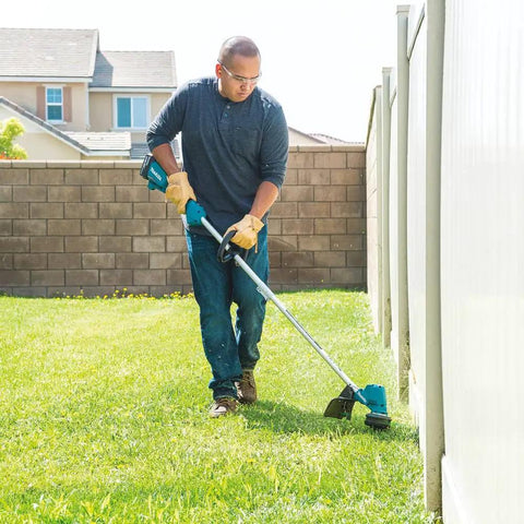 Man using Cordless 13 Inch String Trimmer With Brushless Motor 18V LXT Power 4.0Ah Battery Kit along a garden fence