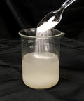 Liquid Lock Slurry Absorbent Powder in action solidifying liquid in a beaker, demonstrating high absorption capacity and fast solidification.