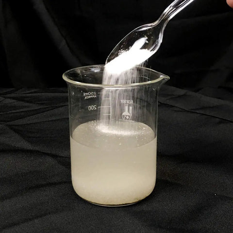 Liquid Lock Slurry Absorbent Powder in action solidifying liquid in a beaker, demonstrating high absorption capacity and fast solidification.
