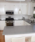 Modern kitchen with stainless steel appliances, white cabinets, and gray countertop