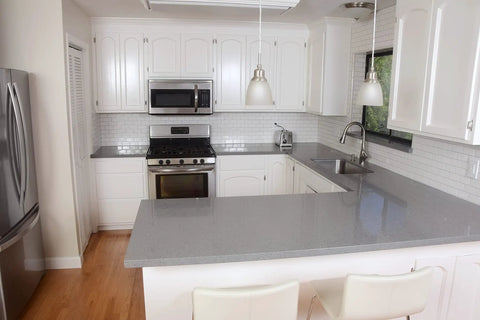 Modern kitchen with stainless steel appliances, white cabinets, and gray countertop