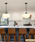 puncoll Vintage Black Milk Glass Pendant Light, 15.7'' White Chandelier hanging above a modern kitchen island with bar stools.