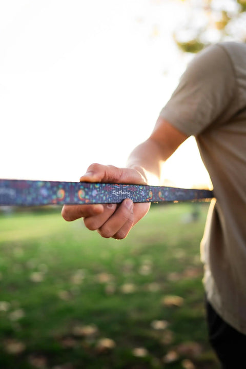 Person holding 1 Inch Slackline Kit With Dual Ratchet System 82 Foot Jungle Line Webbing Two Tone Design outdoors