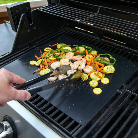 Heavy Duty Grill Mats Set Of 5 Nonstick BBQ Mats For Outdoor Grilling And Indoor Baking Reusable Easy To Clean Works On Gas Charcoal Electric Grills Keep Grates Clean And Flavorful With Extended Warranty in use on a gas grill with vegetables and shrimp.