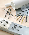 Various drill bits and impact drivers on a wooden surface, including Impact Tough Magnetic Bit Holder For 2 Inch Bits, 1 Piece Design.