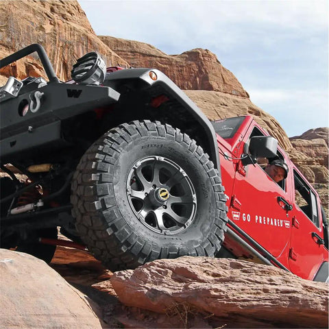 Red off-road vehicle on rocky terrain showcasing Premium Manual Locking Hub Kit With 19 Spline Fit Zinc Aluminum Dial Dual Seals Chrome Finish