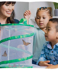 Children observing butterflies in a mesh habitat from the Butterfly Garden Kit With Live Caterpillars, Habitat, Feeder And Chrysalis Holder For Raise And Release Painted Lady Butterflies, STEM Activity Journal Included For Kids And Families, A Fun Kid Friendly Science Project For Classrooms.