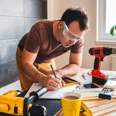 Man using Killer Safety Glasses With Side Shields For Labs Shops And Daily Grinding, writing with tools on table.