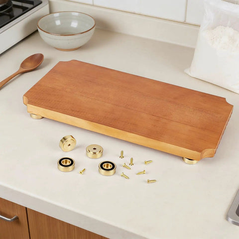 Solid Brass Cutting Board Feet With Grippy Silicone Pads on a wooden board with screws and parts on a kitchen counter.