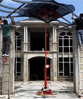 Two workers using a Heavy Duty Roller Shutter Lifting System For Factory Use With Integrated Material Handling Platform to install roofing at a warehouse.