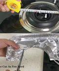 Thick 8.5 Inch Gas Burner Liners 50 Pack Disposable Aluminum Foil Stove Burner Covers being measured and cut for fit