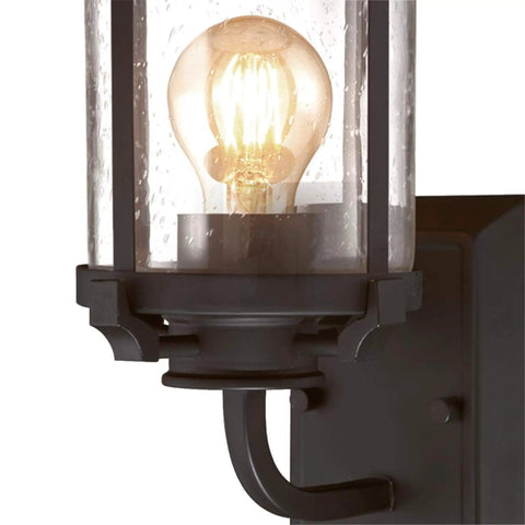 Close-up of Colville Three-Light Indoor Vanity Wall Fixture in oil rubbed bronze with clear seeded glass, showcasing glowing bulb.
