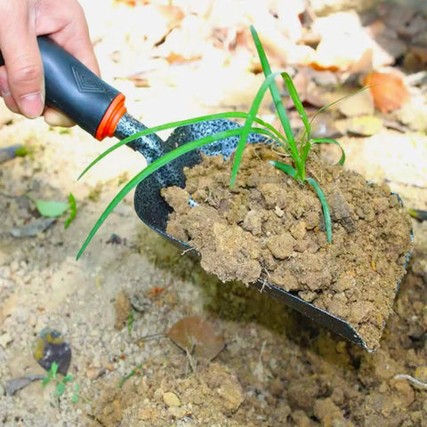 Lightweight Fireplace Shovel 12.6 Inch Ash Shovel scooping soil with a plant, carbon steel head, heat-resistant rubber handle.