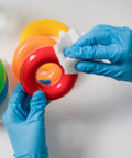 Hands wearing Built Tough Powder Free Nitrile Exam Gloves With Killer Textured Grip cleaning a red toy ring.