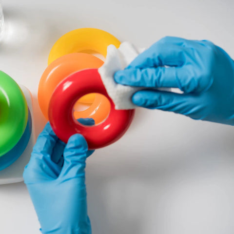 Hands wearing Built Tough Powder Free Nitrile Exam Gloves With Killer Textured Grip cleaning a red toy ring.