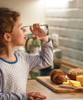 Child drinking water from glass by kitchen counter with bread and cheese, highlighting safe water from Water and Air Filter Combo Pack 2 Piece Set for Select Models WF3CB PAULTRA Reduces Chlorine Taste and Odor Lead Mercury Pharmaceuticals and More Keeps Water Taste Fresh and Fridge Odors In Check.