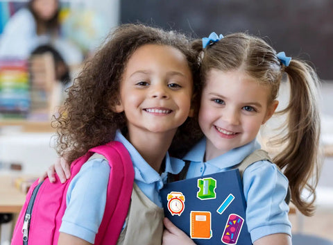 Two children in school uniforms holding notebooks with Totally Back To School Sticker Pack 47 Pcs Waterproof Decals in a classroom.