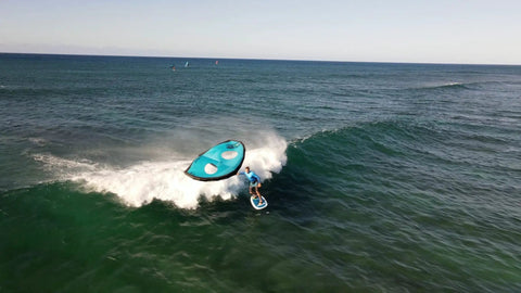Surfer using Alien Wing 6M High Performance Wind Wing For Foiling And Surfing Lightweight Aerodynamic Rigid Wing Includes Backpack Wrist Leash And Repair Kit Tri Color on ocean wave.