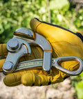 Gloved hand holding Haven's Grip For Messenger And Guy Strand Cable, Light Duty, Grippy Knurled Jaw Tool, Gold Finish, outdoor setting