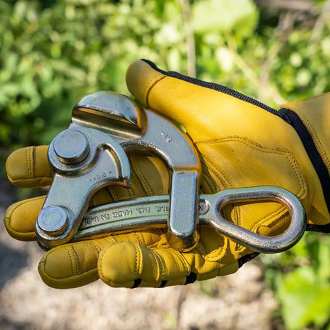 Gloved hand holding Haven's Grip For Messenger And Guy Strand Cable, Light Duty, Grippy Knurled Jaw Tool, Gold Finish, outdoor setting