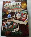 Gravity Falls DVD box with colorful characters, labeled Complete Animated Series Collector Edition On DVD With All Episodes Must Have Family Friendly Binge Worthy Adventure Mystery And Humor Packed Set Deluxe Collector Packaging Bonus Features Included.