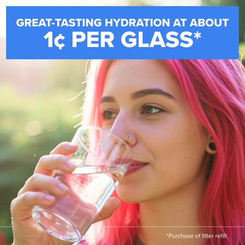Close-up of a woman with bright pink hair drinking water from a clear glass outdoors.