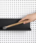 Hand placing a hammer on a Six Pack Magnetic Pegboard Shelf with lip edge for garage and workshop, metal pegboard tray, wall mount.