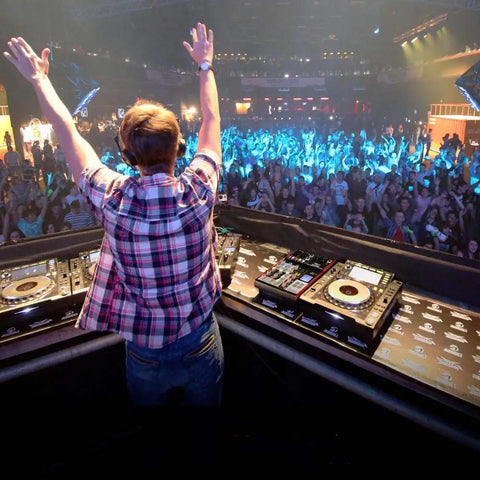 DJ performing on stage with Six Channel Bluetooth DJ Mixer And USB Audio Interface For Home Studio Recording Portable Digital Mixing Console With Independent Channel Gain EQ FX Send And Master Control PMXU68BT in crowded club.