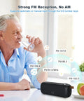 Bluetooth Speaker With FM Radio And 5 In 1 Music Player on table with FM bands; man drinking water in background.