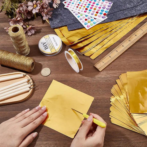Metal Sheet Embossing Kit For Tin Foil Art And Embellished Designs with tools, gold foil sheets, and copper wire on a table.
