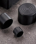 Three rubber chair leg tips in various sizes on a textured surface, non scratch floor protectors for hardwood furniture.
