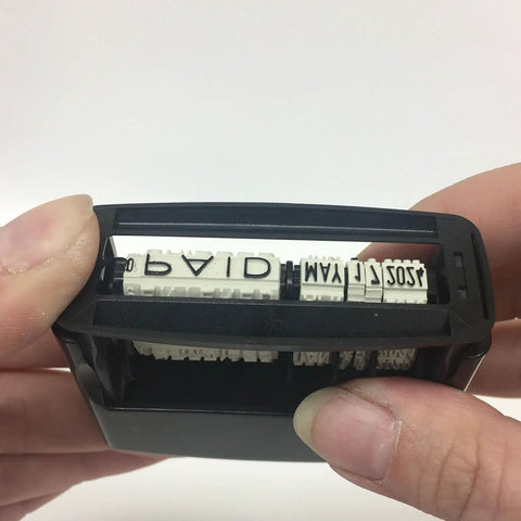 Close-up of Premium Self Ink Date Stamp Featuring Dial Phrase Adjuster displaying text, sturdy black rubber build for daily usage.