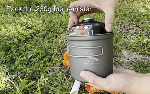 Hands placing a fuel canister into Titanium 1100ml Pot And Pan Set For Backpacking Ultralight Outdoor Cooking Gear on grass