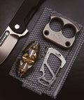 Stainless Steel 7 Tool Carabiner Clip Multitool with knife, brass decor, and metallic item on patterned fabric background
