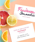 White business cards on a peach and teal background with citrus slices; front card displays Fruiteeza Smoothies logo.
