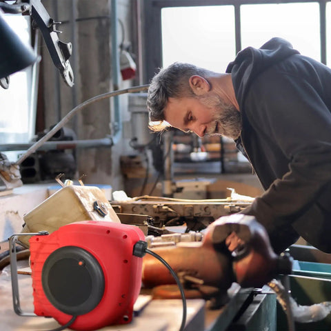 Man using Heavy Duty 50ft Retractable Extension Reel with 14AWG 3C SJTOW Cord in workshop setting