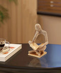 Sparkling Gold Tone Reading Woman Statue With Beaded Surface Modern Abstract Figurine on table beside book and teacup