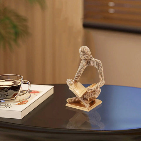Sparkling Gold Tone Reading Woman Statue With Beaded Surface Modern Abstract Figurine on table beside book and teacup