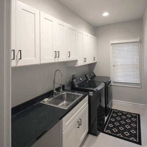 Laundry room with white shaker cabinets, black countertop, stainless steel sink, washing machine, and dryer.