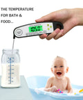 Hand using digital meat thermometer for grilling with backlit display over milk bottle, baby in tub nearby