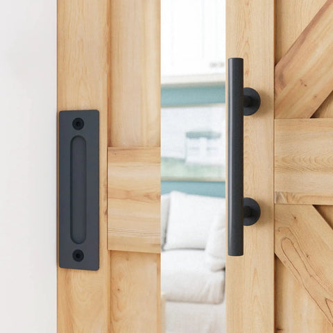 All In One Heavy Duty Sliding Barn Door Hardware Kit Features 11 Foot Track With Whisper Quiet Nylon Rollers For Rock Solid Reliability Smooth Silent Operation Dead Simple Install Durable Alloy Frame No Door Included Matte Black Finish close-up of matte black door handle and plate on wood barn door.