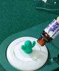 Smart Cup Warmer Heating Pad With Adjustable Temperature Controls Keeping a cactus-shaped essential oil dropper on a marble base.