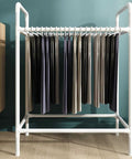 Space Saving Trouser Rack With 15 Heavy Duty Pants Clips And Smooth Wheels holding neatly hung pants in a white steel frame.