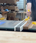 SavR Push Block For Table Saw And Router Table, With Magnetic Fence Mount in use, guiding wood past blade safely in workshop