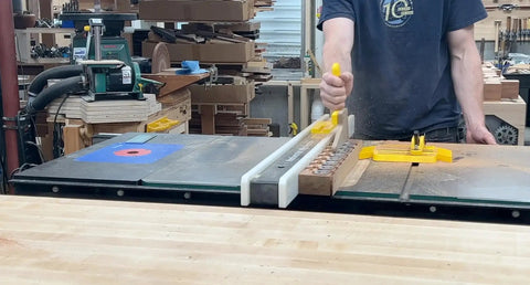 SavR Push Block For Table Saw And Router Table, With Magnetic Fence Mount in use, guiding wood past blade safely in workshop