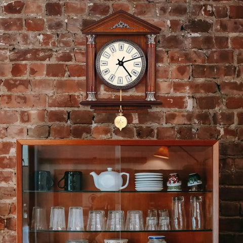 Durable Metal Pendulum Replacement For Wall Clocks And DIY Timepiece Projects under a vintage wooden clock on brick wall