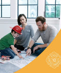 Family planning fire escape route with toy fire truck and map indoors, child wearing red firefighter helmet.