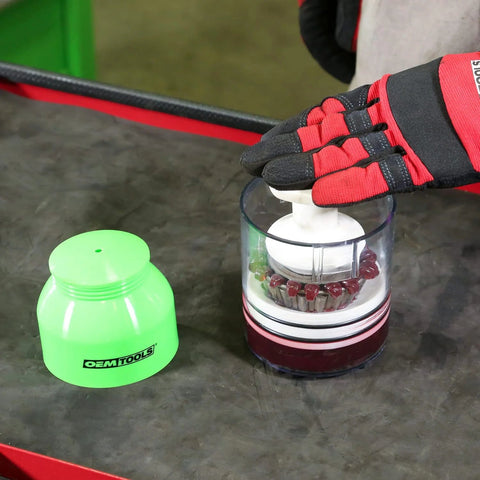 Front view of OEMTOOLS bearing packer with transparent grease cup and white plunger; green cap nearby.