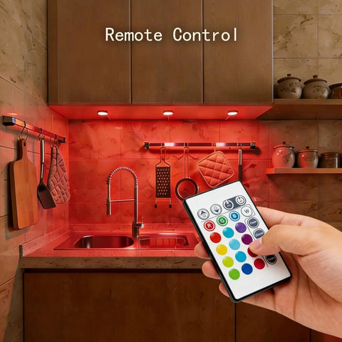 Under Cabinet RGB LED Puck Lights Kit With Wireless Remote Control 16 Color Dimmable Plug In Lights For Kitchen Bookshelf Counter 4 Pack No Fuss Easy Plug In Setup And Remote Dimming showing remote control usage in kitchen